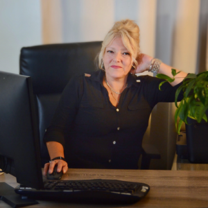 Photo of Nathalie Mallette at her desk with her hand behind her head.